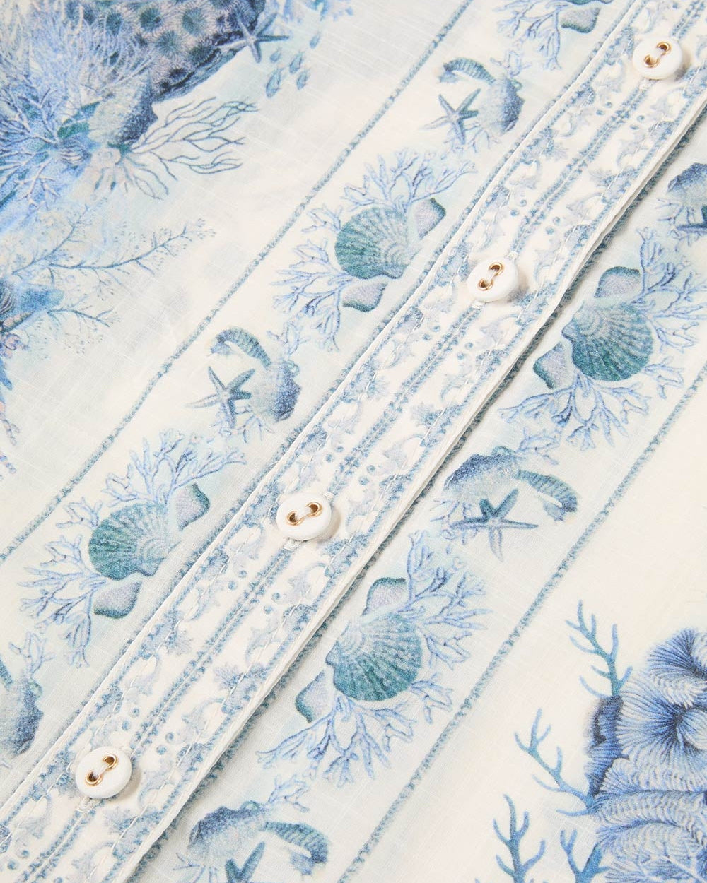 Close-up of a decorative fabric with blue sea-themed patterns and white buttons.